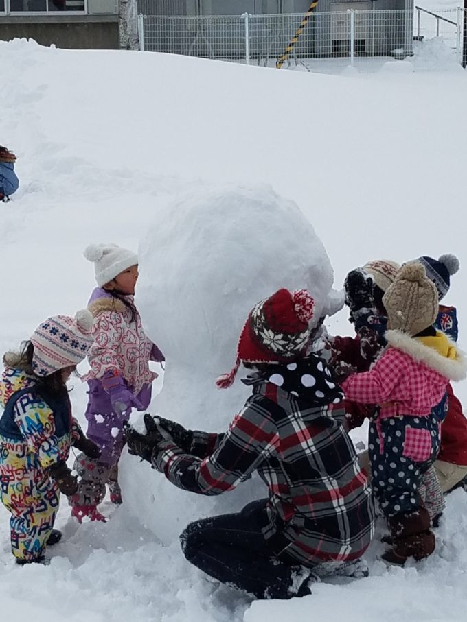 雪だるまを作っている園児たち