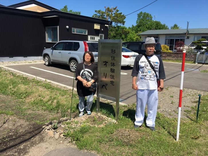 オリベの看板の横で写真を撮るKさん