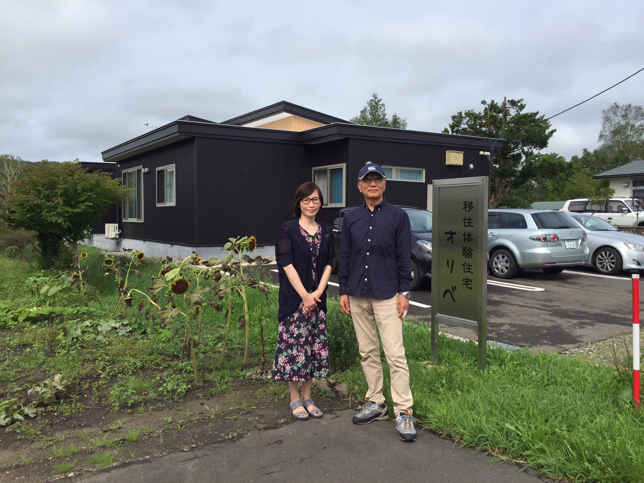 オリベの看板の横で写真を撮るIさん