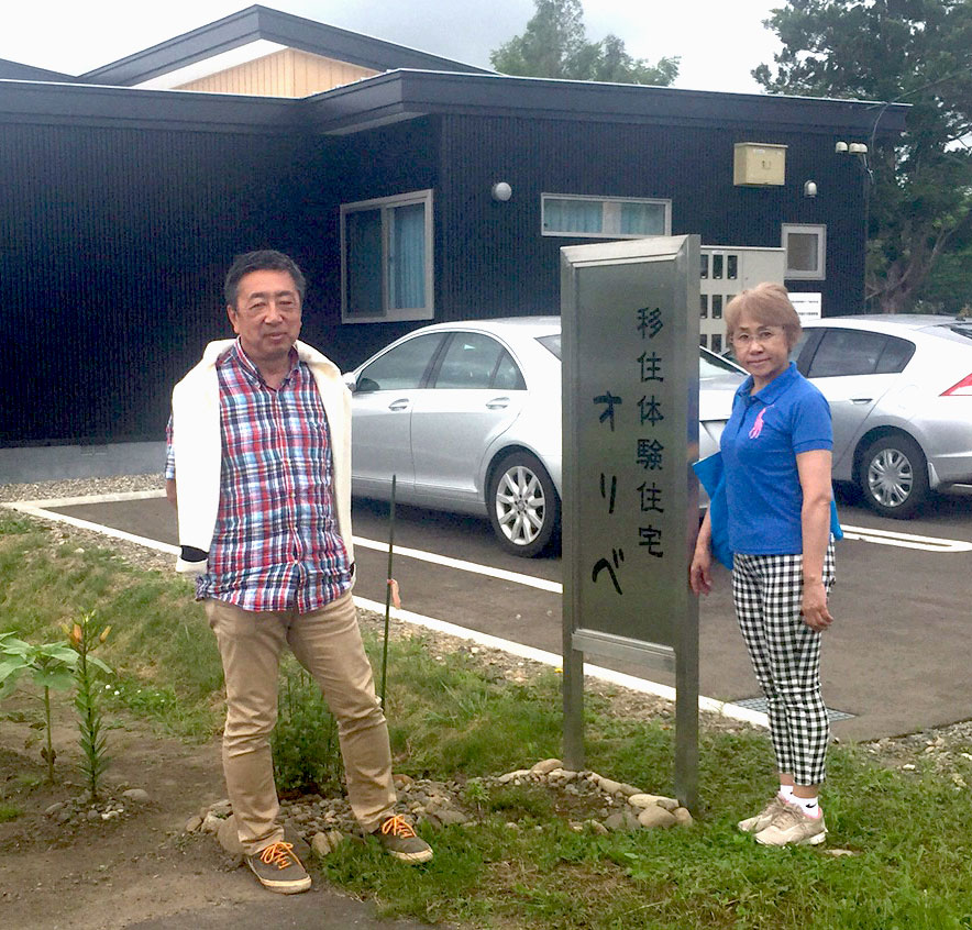 オリベの看板の横で写真を撮るSさん