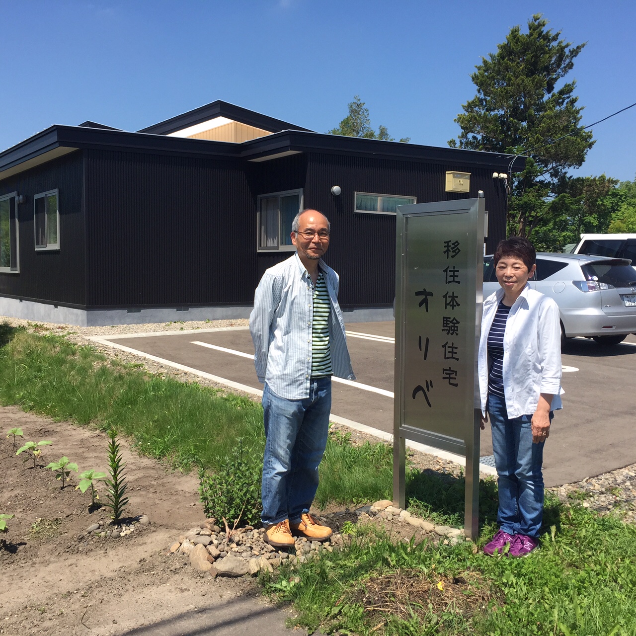 オリベの看板の横で写真を撮るTさん